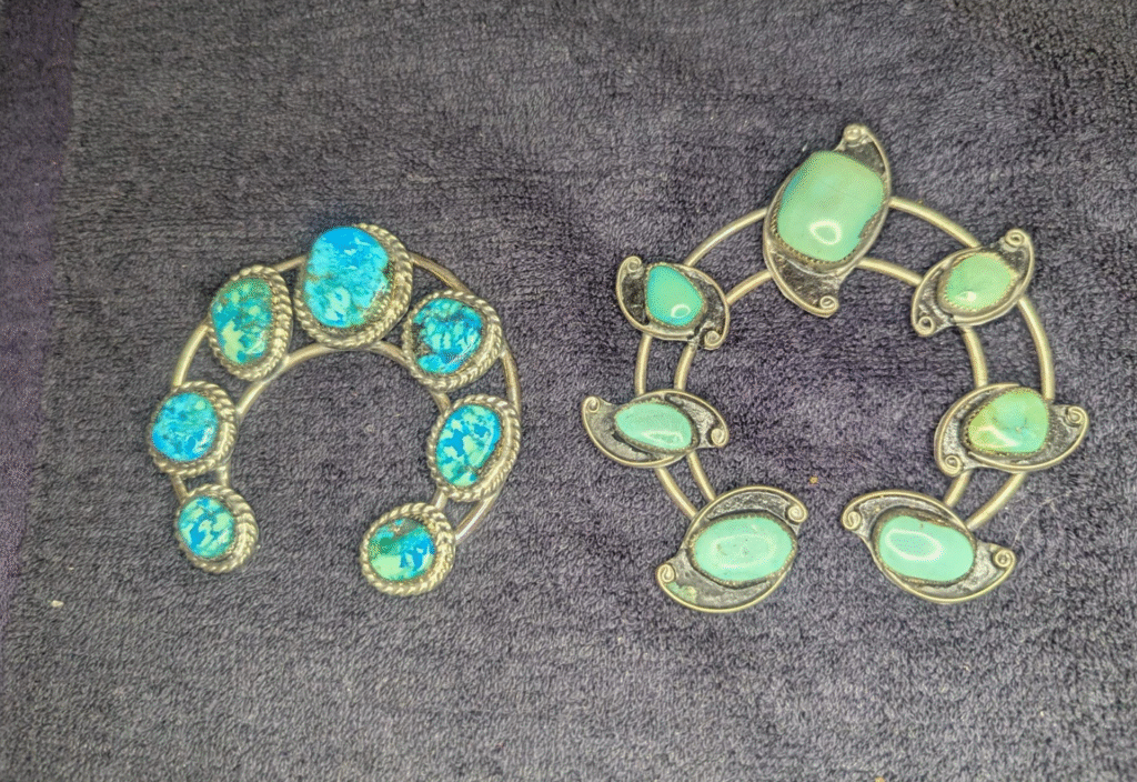 Photograph of one of the lots in this vegas estate sale auctions, lot#594- two horseshoe shaped pendants with turquoise stones inlaid  in what appears to be a precious metal.